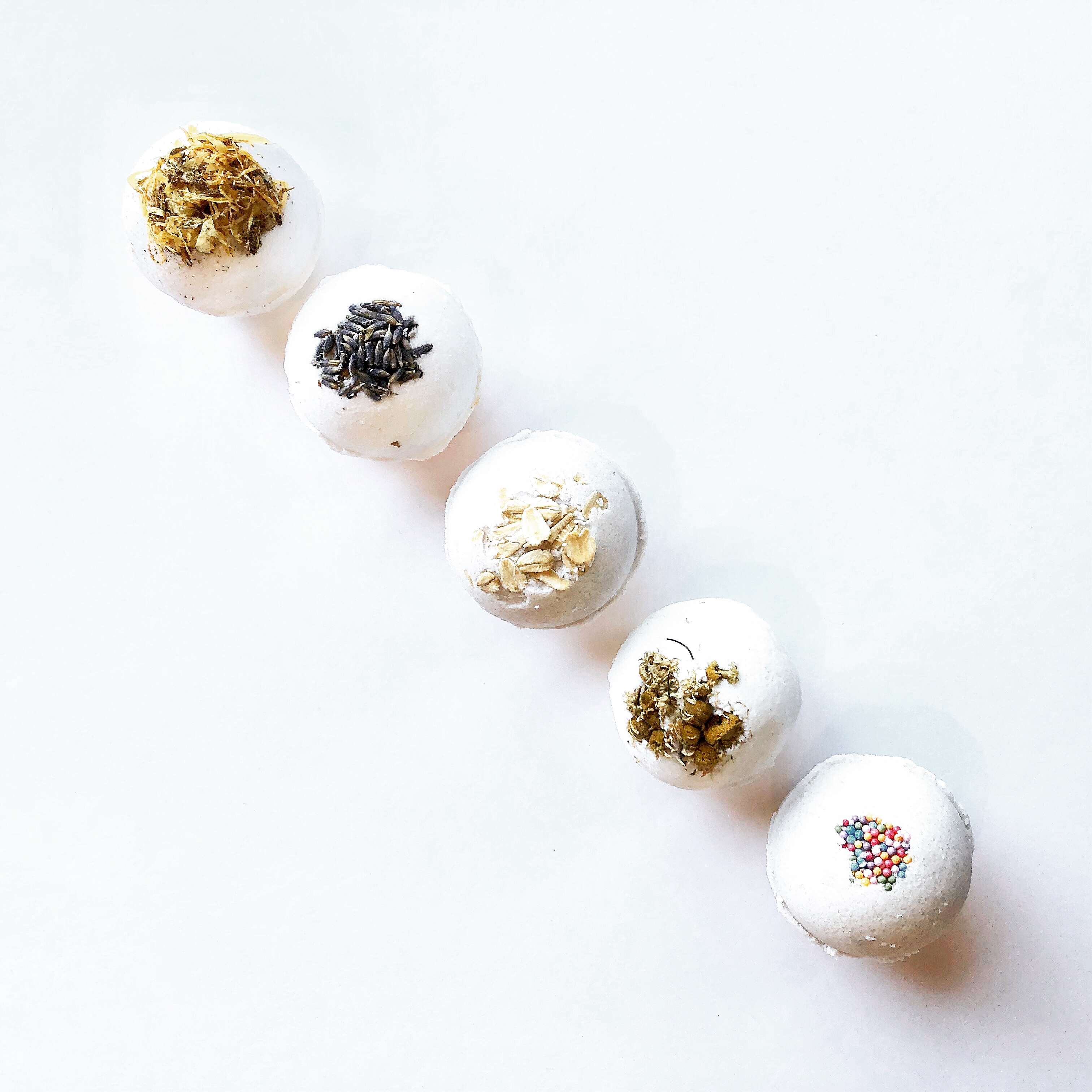 Homemade bath bombs decorated with lavender, oats, german chamomile, calendula, and organic sprinkles. #diybathbombs #homemadebathbombs #nontoxicbathbomb #bathbombrecipe