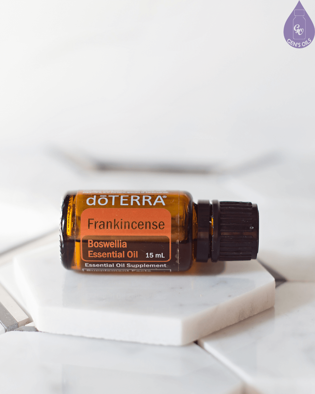 A bottle of doTERRA Frankincense essential oil rests on a white marble hexagon tile.