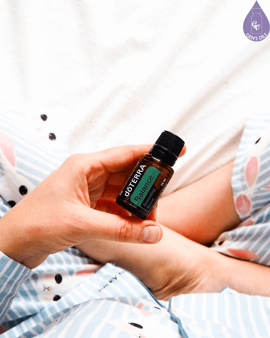 A person holds a small bottle of doTERRA Balance essential oil.