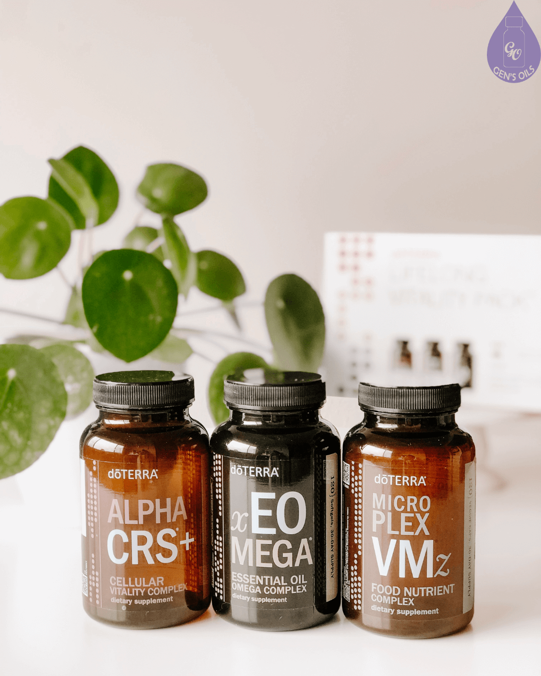 Three doTERRA supplement bottles: Alpha CRS+, EO Omega, and Micro Plex VMz, with a green plant and a box in the background.