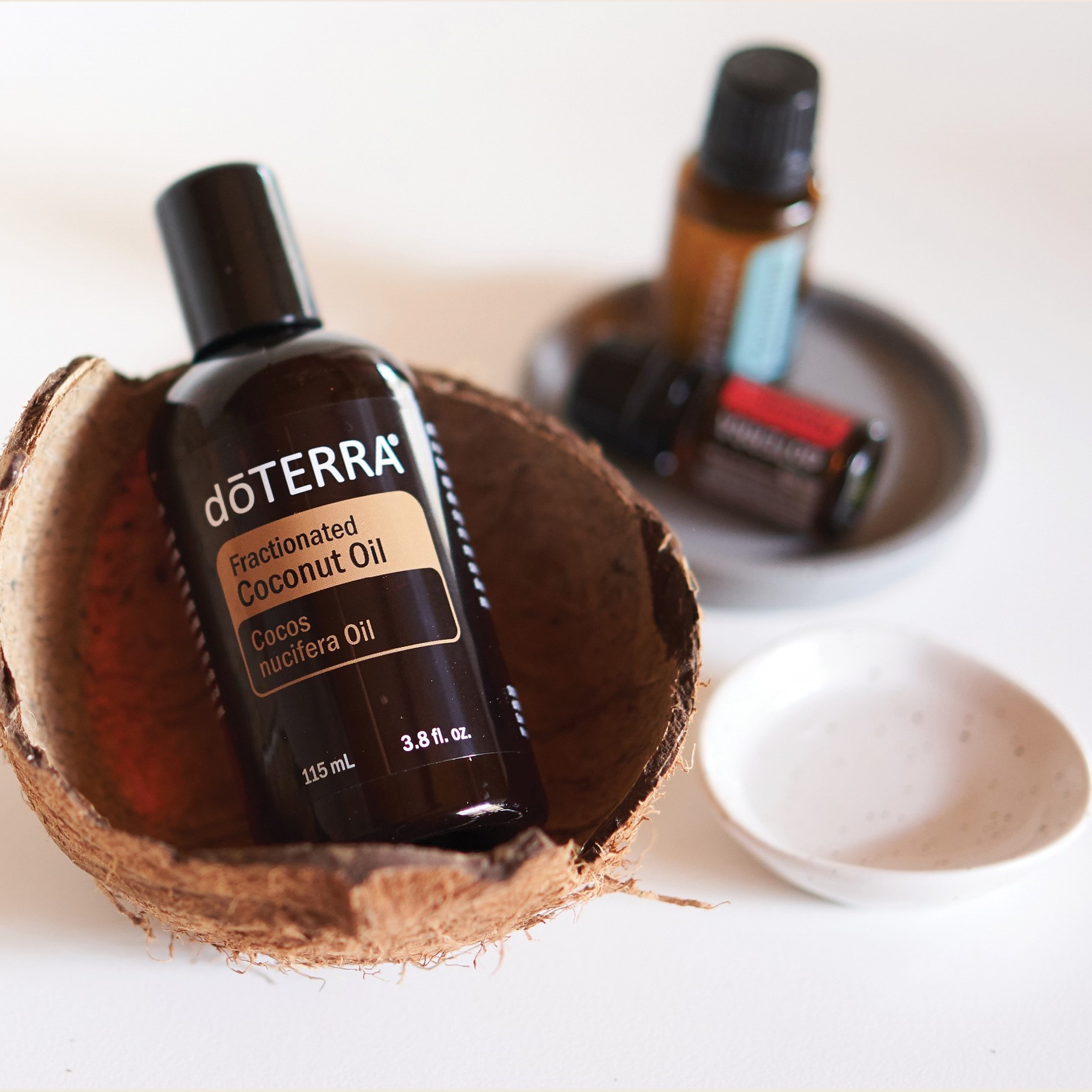 A bottle of Fractionated Coconut oil in a coconut husk with small dish beside it.