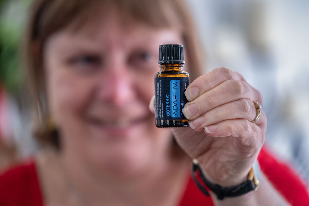 Holding up a bottle of Adaptiv essential oil
