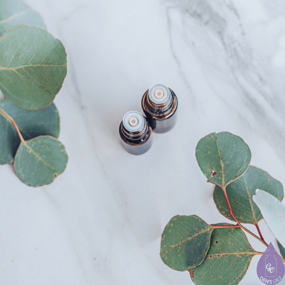Two open bottles of essential oils on a marble like background with greenery.