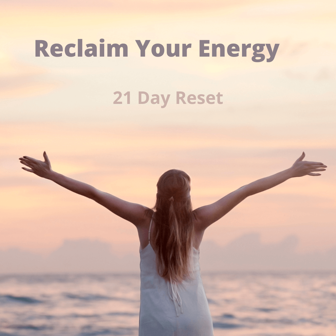 A woman looking over the sea with her arms spread wide above her head.