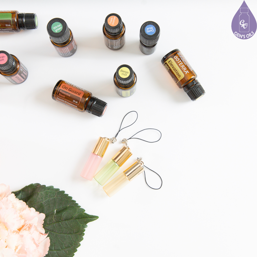 A group of doTERRA 15 ml essential oils with pretty roller bottles and pink flowers.