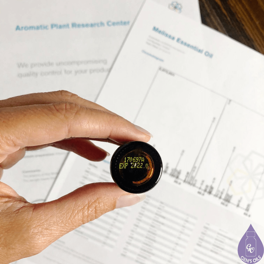 A hand holding a bottle of essential oil with the code on the bottom showing.