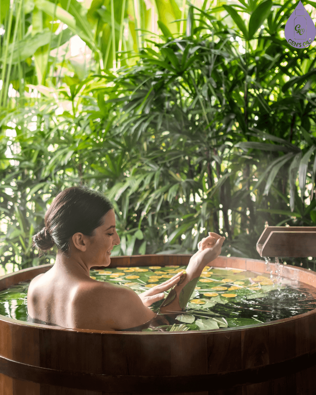 A person relaxes in a wooden tub filled with water and greenery, surrounded by lush foliage.