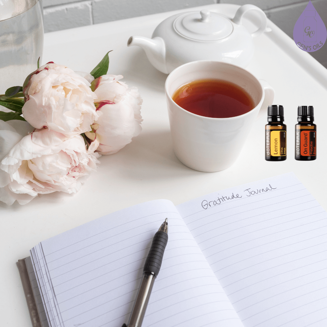 Notebook, pen, tea, flowers, Lemon & On Guard essential oils on bedside table.