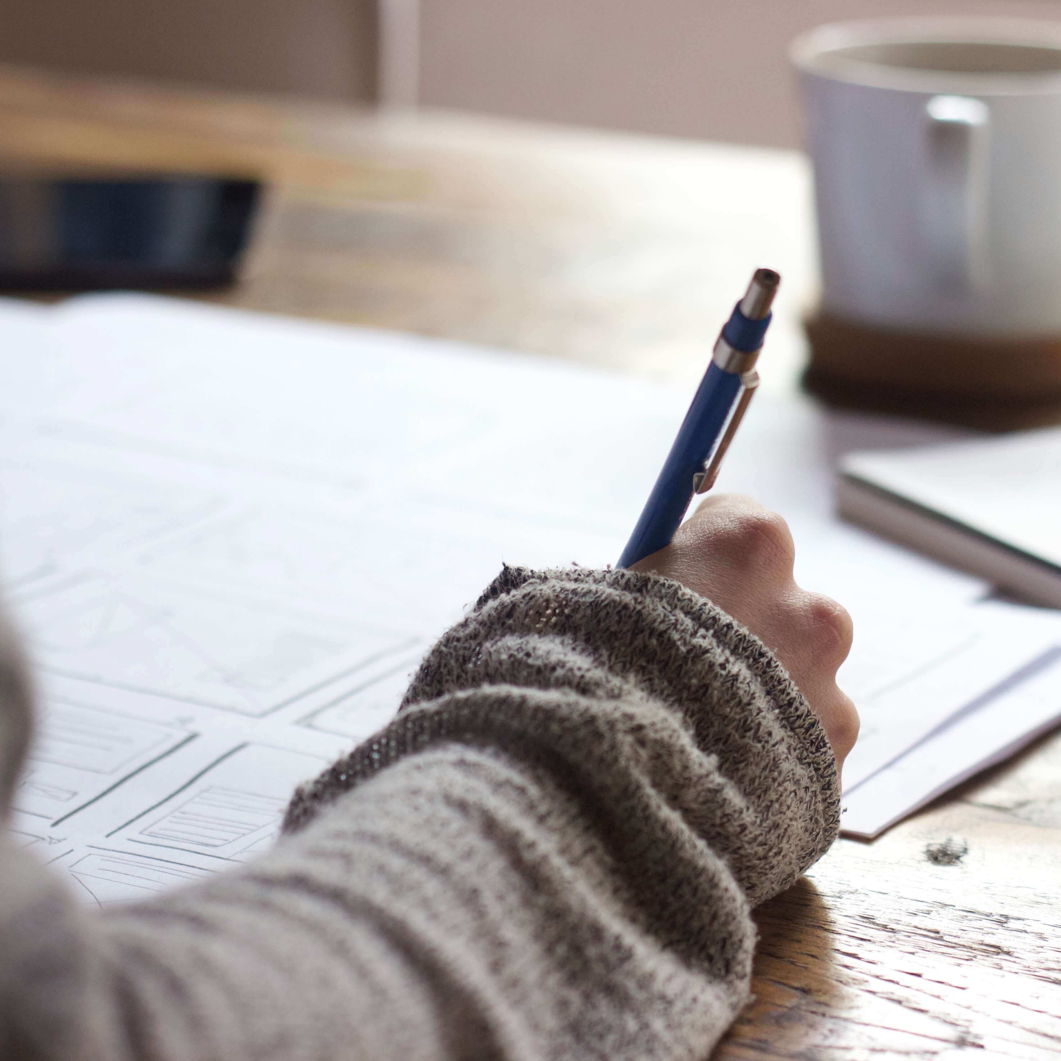 cozy sweater arm and hand holding pen writing at desk