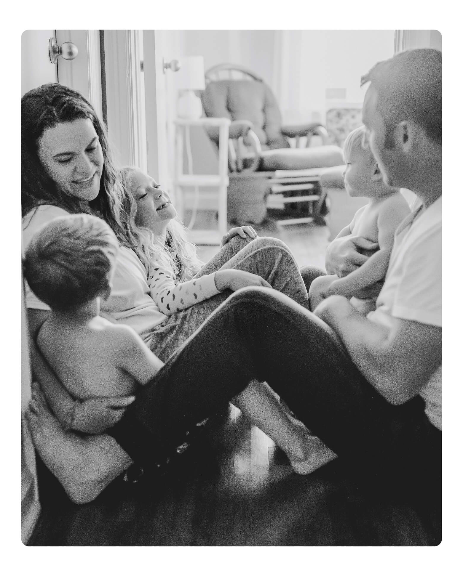 A family with baby sits on a living room floor