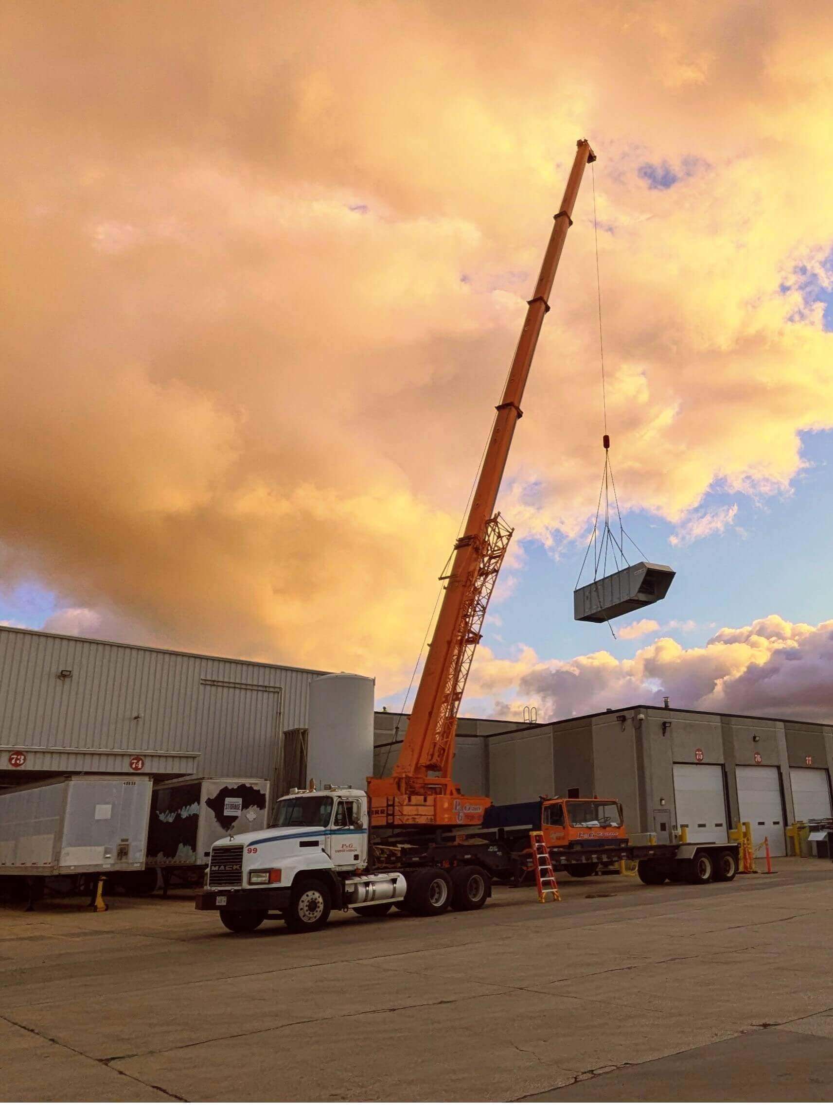 Crane lifting a unit over a building in the sunset.