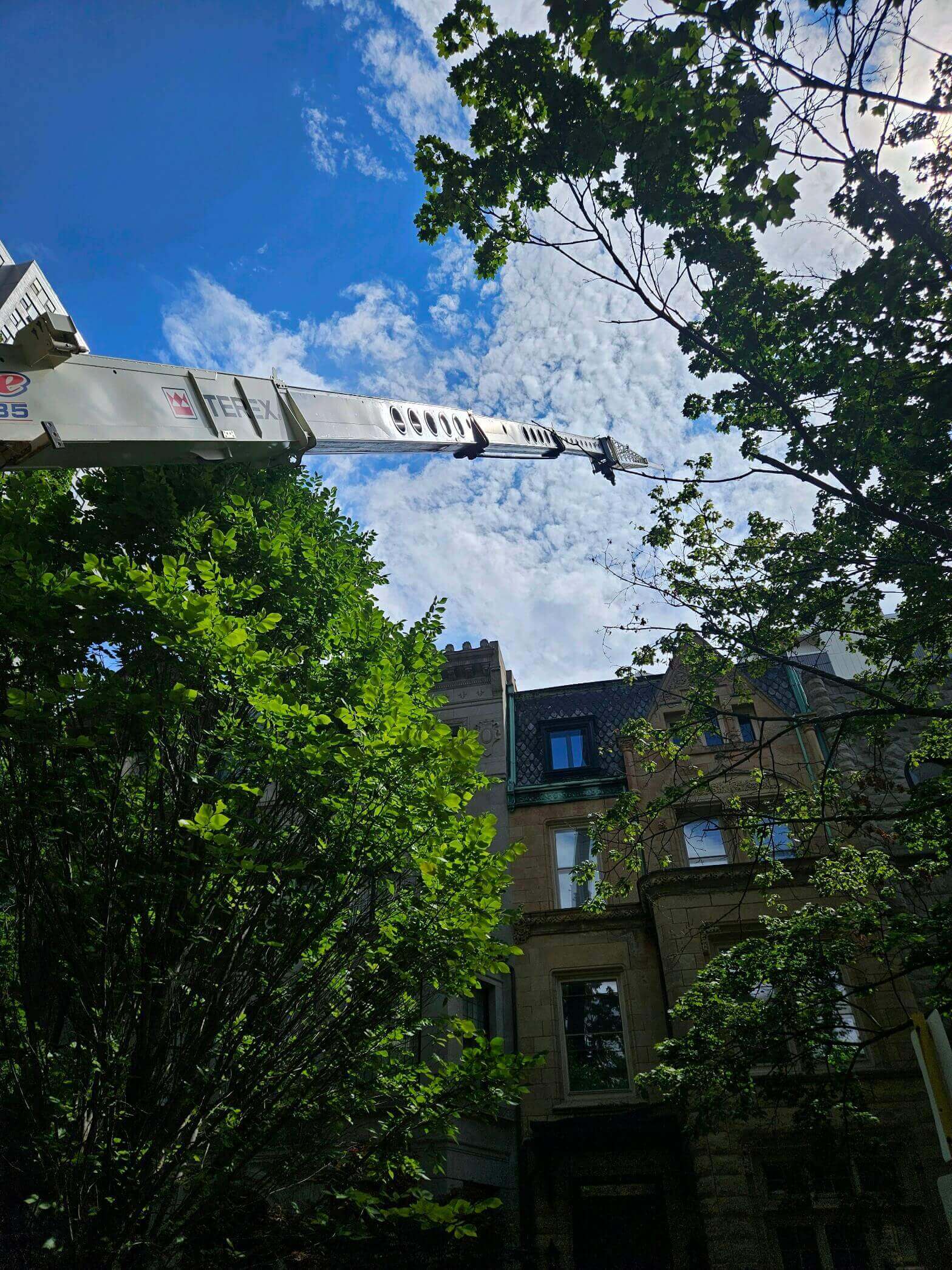 Crane boomed up next to a building.