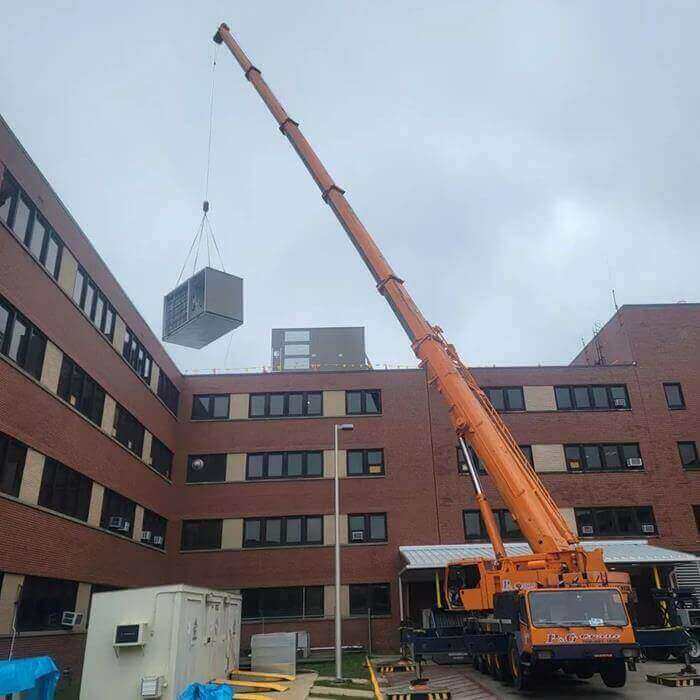 Crane lifting unit over building.