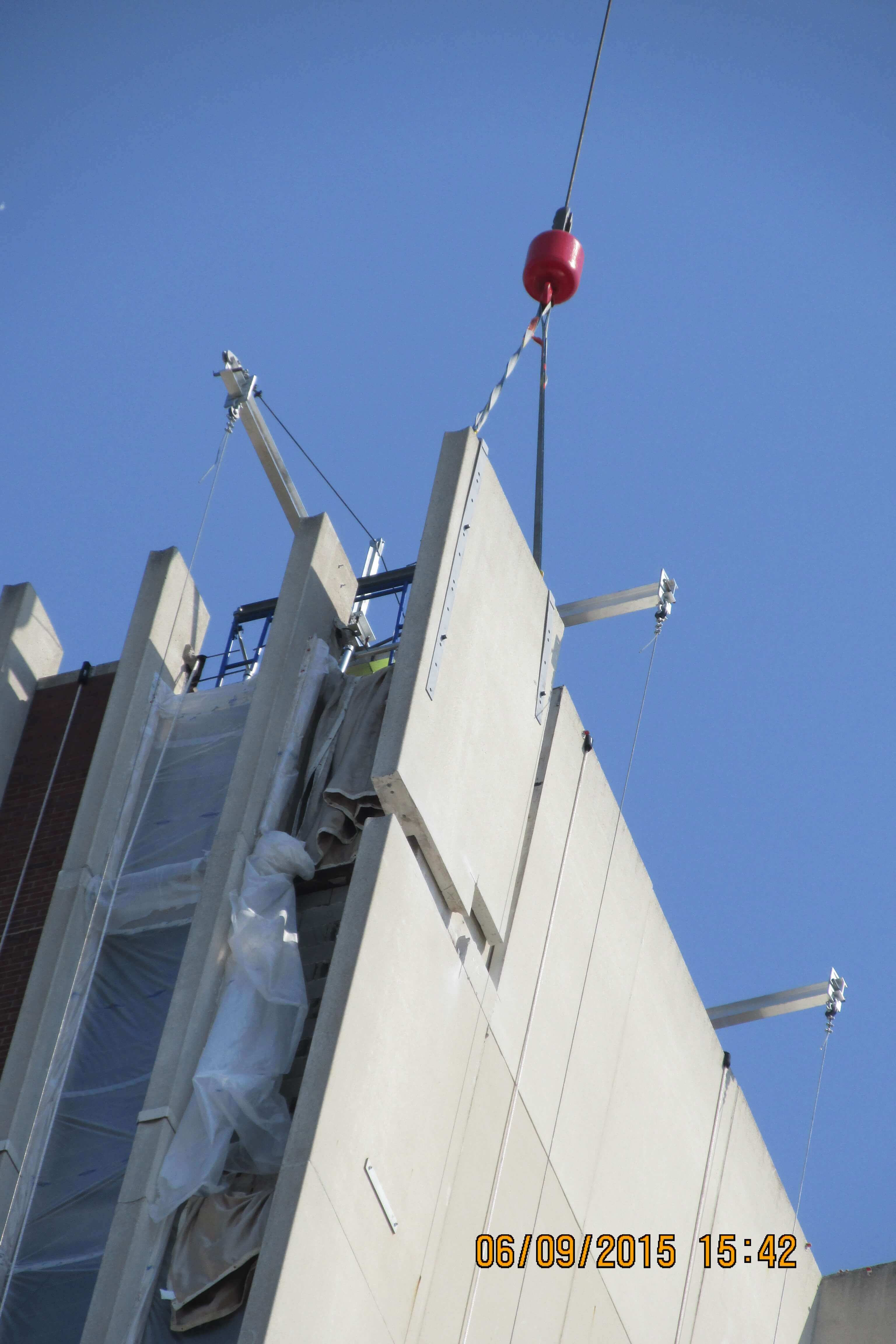 Crane removing a section of the outer wall on building.