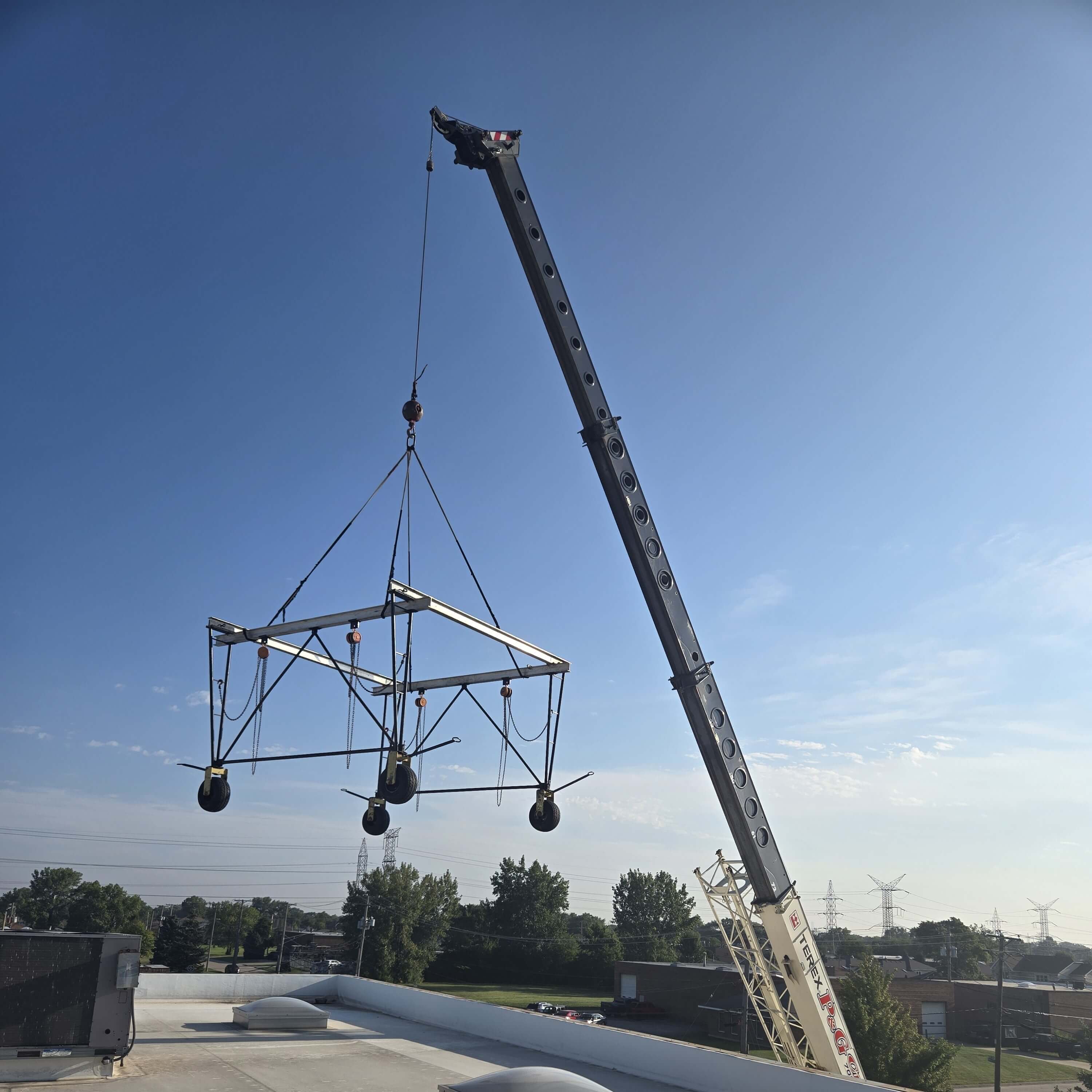 Gantry crane being transported to the top of a roof by a crane.