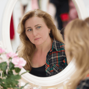Semi-Permanent Makeup Middlesbrough – Woman looking in the mirror, considering semi-permanent makeup at Helena Aesthetics in Middlesbrough for effortless beauty.